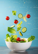 Fresh salad ingredients splashing into white bowl