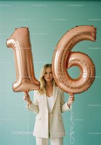 Young woman holding rose gold number 16 balloons