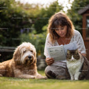 Woman Reading Paper Outdoors with Dog and Cat