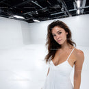 Young Woman in White Dress Posing in Modern Studio