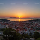 Scenic Sunset Over Coastal Town With Red Rooftops and Seaside Views