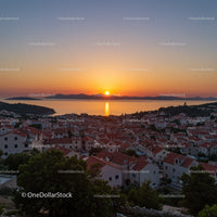 Scenic Sunset Over Coastal Town With Red Rooftops and Seaside Views