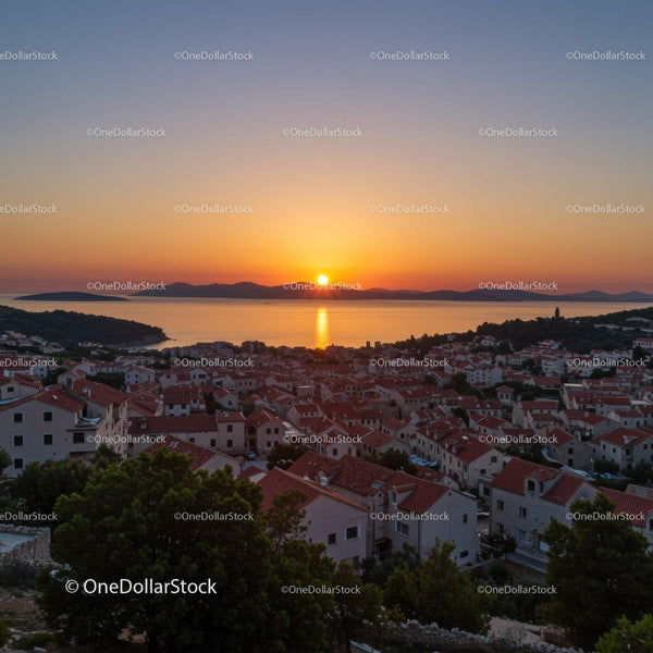 Scenic Sunset Over Coastal Town With Red Rooftops and Seaside Views