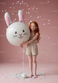 Redheaded girl holding bunny balloon with confetti
