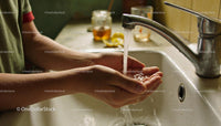Person Washing Hands Under Running Faucet in Kitchen Sink