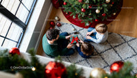 Father Sharing Christmas Gift with Children by Tree