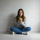 Young woman holding a green apple sitting cross-legged