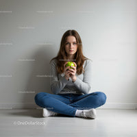 Young woman holding a green apple sitting cross-legged