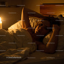 Woman Relaxing in Bed with Candles in a Cozy Atmosphere