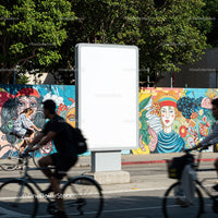 Urban cyclists passing blank billboard with colorful mural