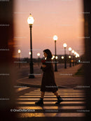 Woman walking alone with roses under streetlights at dusk