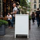 Empty white signboard on busy street with pedestrians