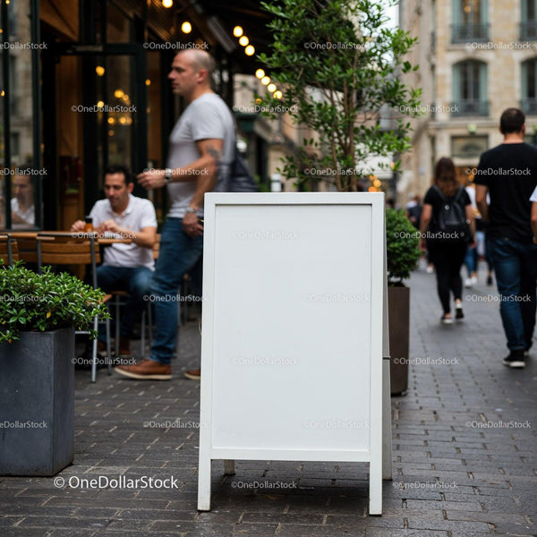 Empty white signboard on busy street with pedestrians JPG Mockup Image