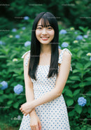 Young Woman in Polka Dot Dress Smiling in Garden with Hydrangeas