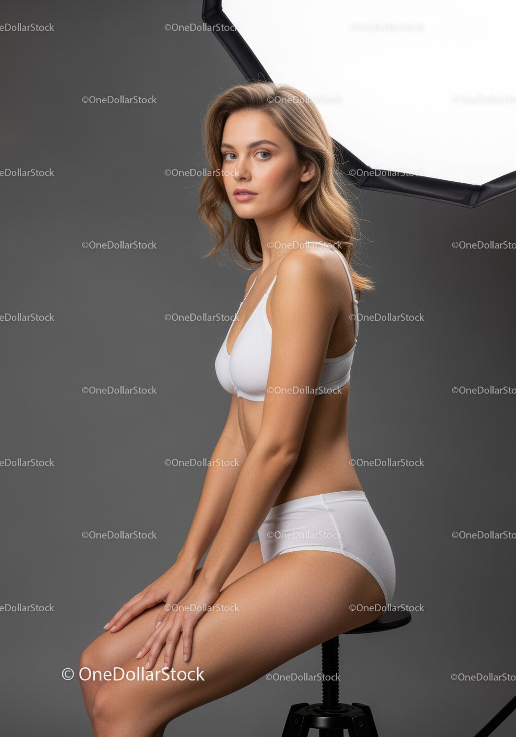Elegant Young Woman in White Lingerie Sitting on Stool in Studio