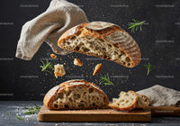 Rustic sourdough bread with flying crumbs and herbs