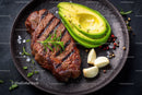Juicy Grilled Steak with Fresh Avocado and Garlic on Dark Plate