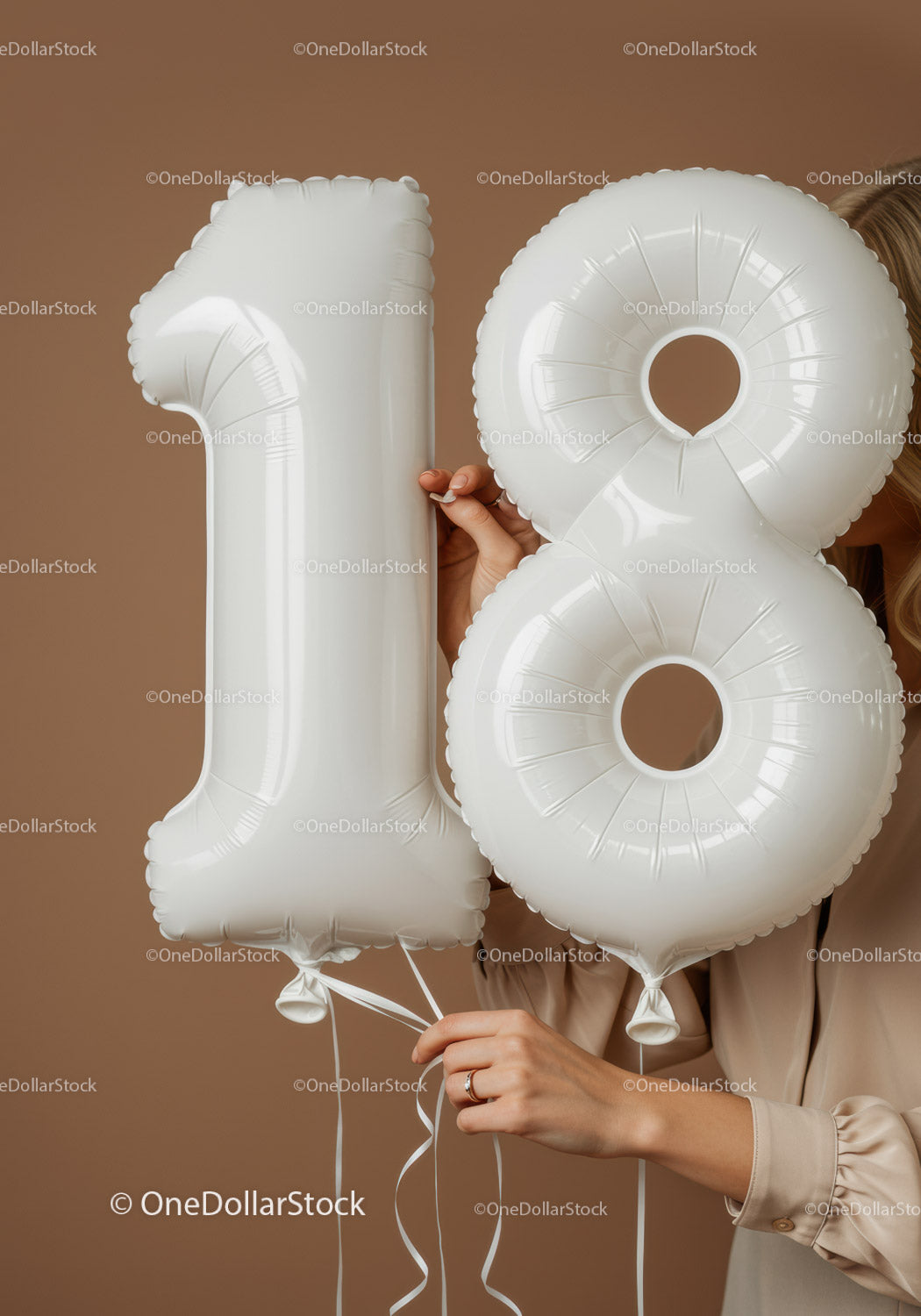 Hands holding white number 18 balloons with beige background
