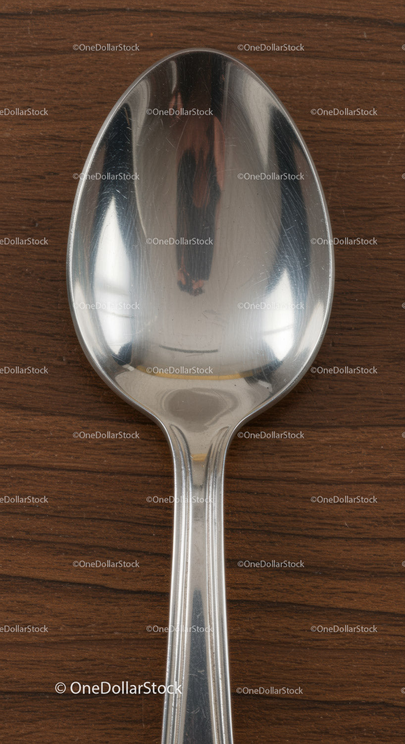 Close up of stainless steel spoon on wooden surface