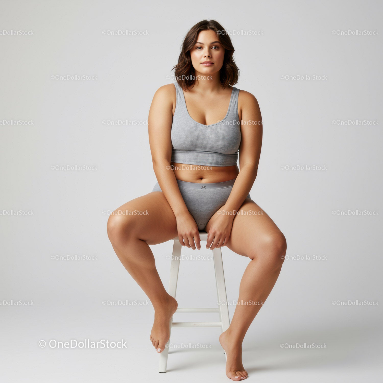 Confident Woman Sitting on Stool Wearing Gray Sportswear for Fitness and Lifestyle