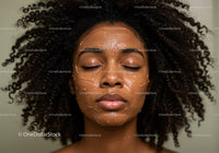Close-up of a woman with natural curly hair applying facial mask