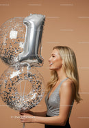 Smiling woman holding silver number one balloons