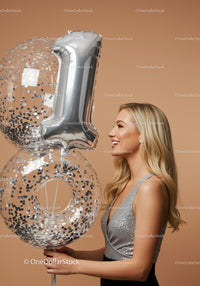 Smiling woman holding silver number one balloons
