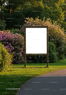 Blank signboard surrounded by blooming pink bushes in park
