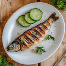 Grilled Whole Fish with Cucumber Slices on Rustic Wooden Table