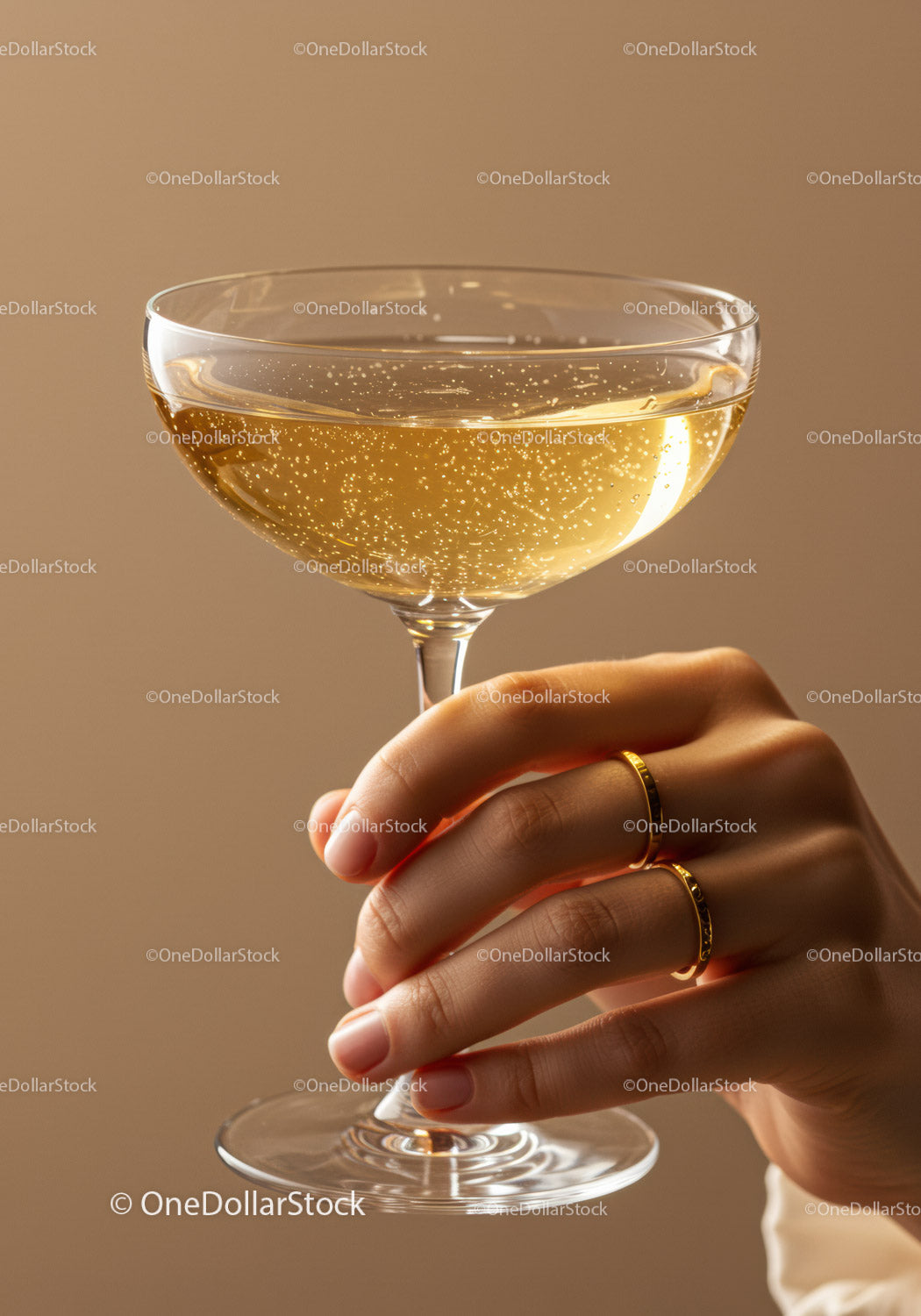 Hand holding sparkling champagne glass with golden rings