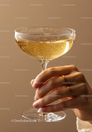 Hand holding sparkling champagne glass with golden rings