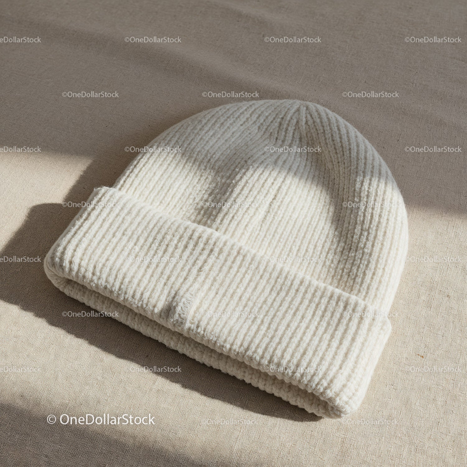 Miękka biała dzianinowa czapka beanie na powierzchni materiałowej