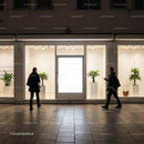 People passing by illuminated modern storefront at night