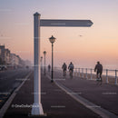Cyclists riding on coastal promenade at sunrise