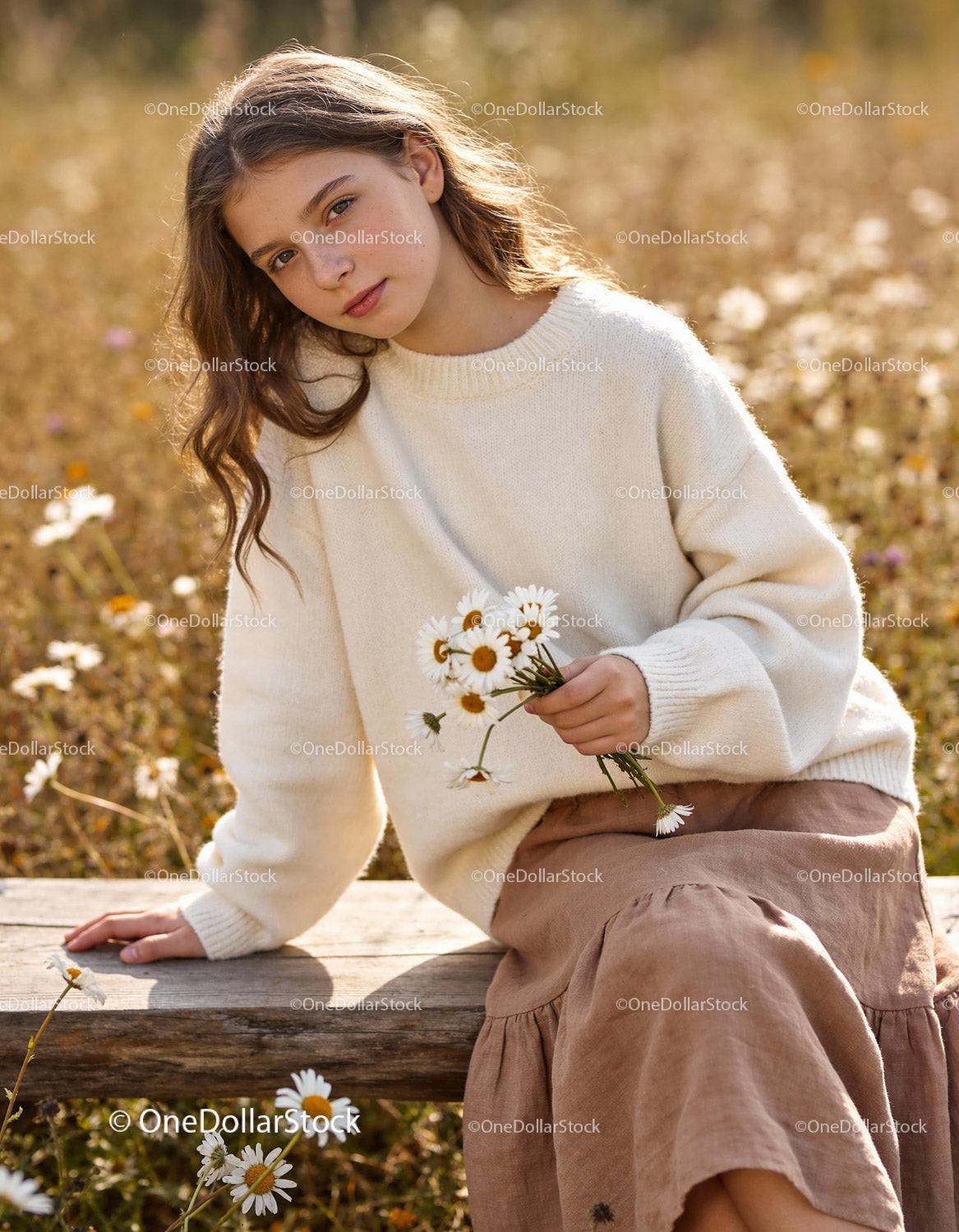 Young woman holding daisies sitting on wooden bench