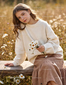 Young woman holding daisies sitting on wooden bench