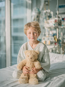 Smiling Young Boy in Hospital Room Holding Teddy Bear