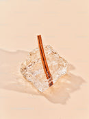 Cinnamon Stick Embedded in Clear Ice Cube on Beige Surface
