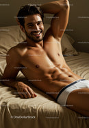 Smiling muscular man relaxing on bed in white underwear