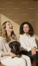 Two women bonding with dachshund on sunny afternoon
