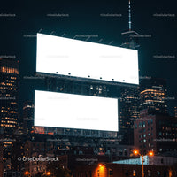 Blank illuminated billboards over city buildings at night