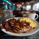 Stack of Fluffy Pancakes with Bacon and Syrup in Cozy Breakfast Setting