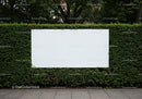 Blank billboard on green hedge in urban setting