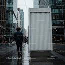 Man walking beside blank white urban billboard on wet city street JPG Mockup Image preview
