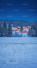 Cozy winter village glowing warmly in snowy forest