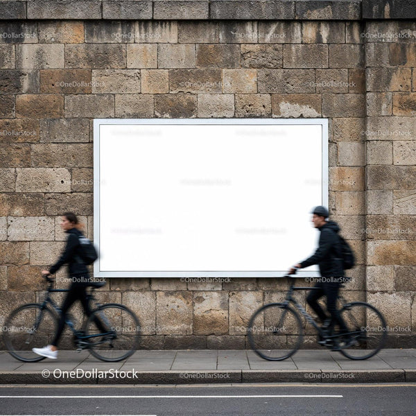 Two cyclists passing blank billboard on stone wall JPG Mockup Image