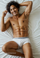 Relaxed young man lying on bed in white underwear