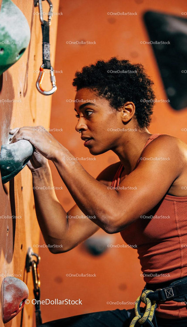 Focused woman climbing indoor rock wall with determination