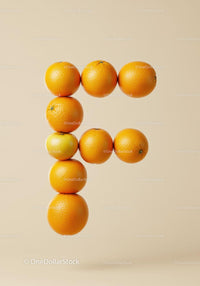 Letter F created from fresh oranges on beige background
