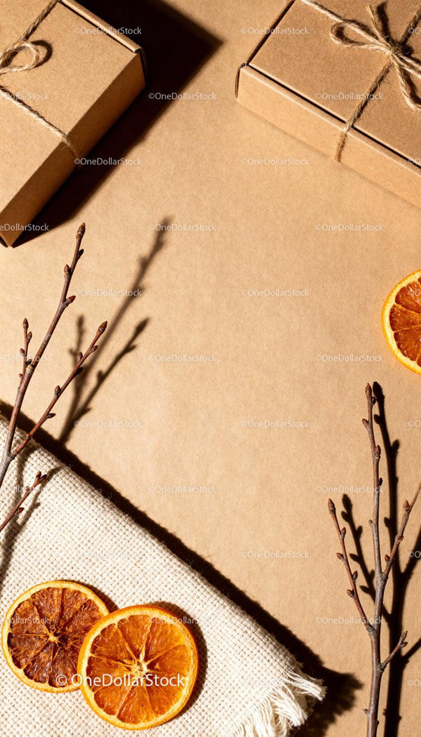 Crafted gift boxes with dried orange and branches on kraft paper